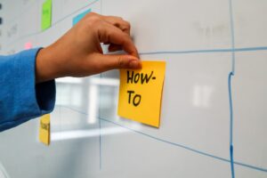a person putting how to sticky note on a wall