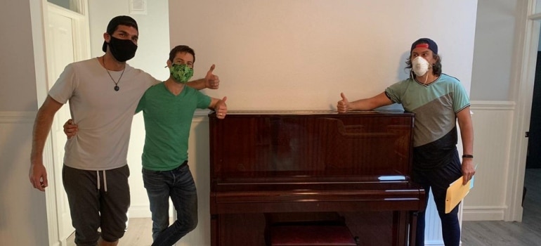 Movers standing next to a piano