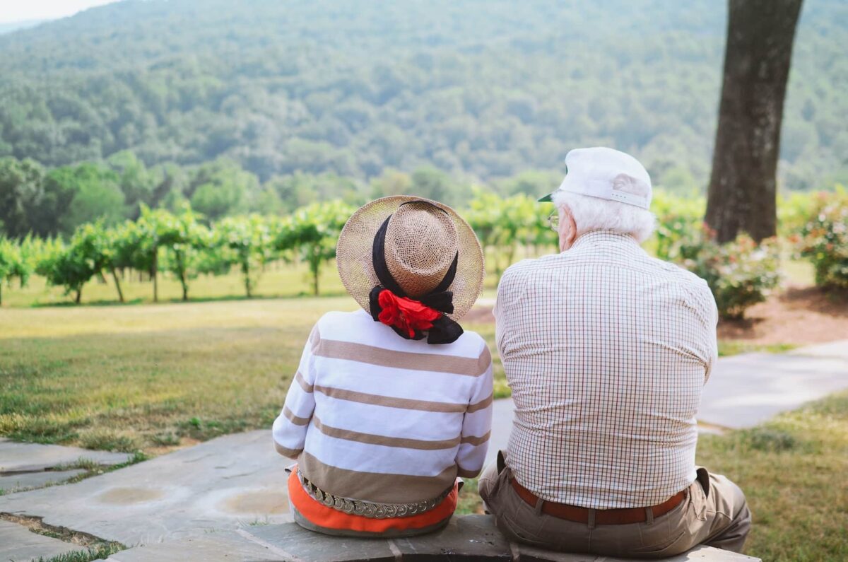 An elderly couple sitting next to each other while appreciating the beauty of nature