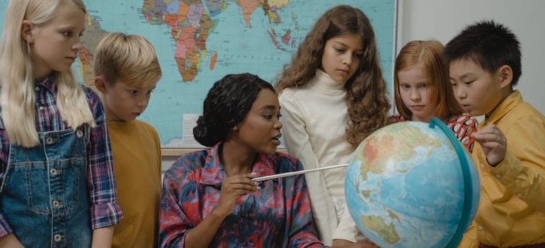 a teacher showing her students a globe